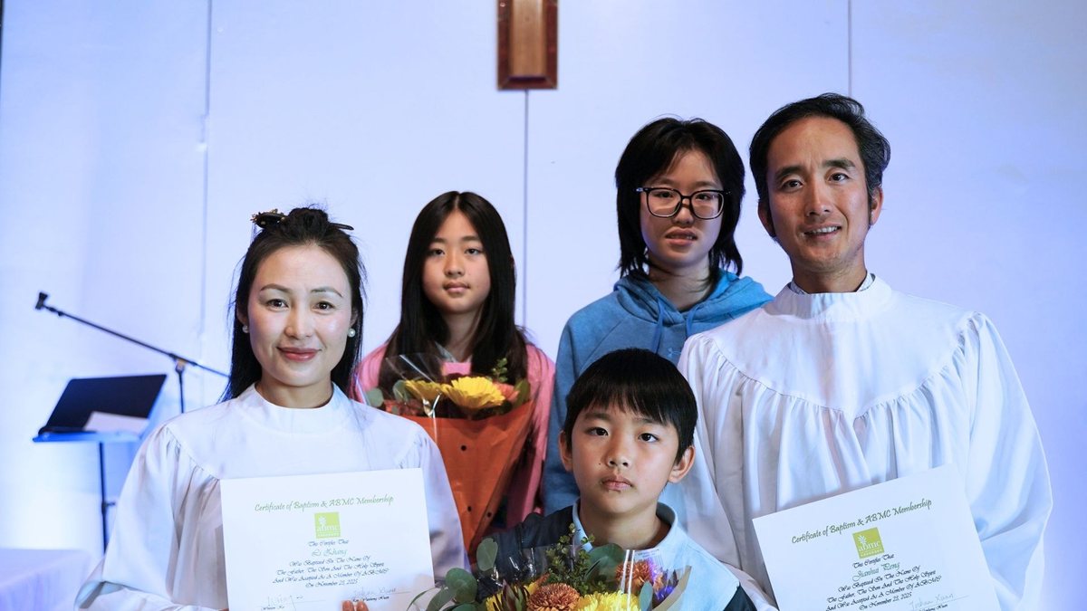 刚受洗的弟兄与太太、孩子一起站着拍照,手里拿着证书