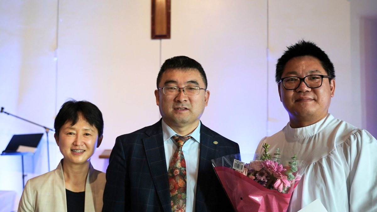 受洗的弟兄抱着花,与牧师、师母一起合照