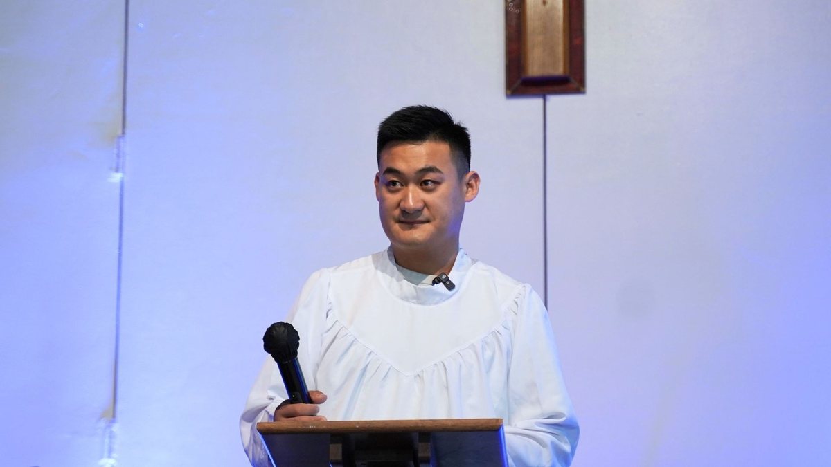 穿着白袍的弟兄站在讲台前作受洗见证