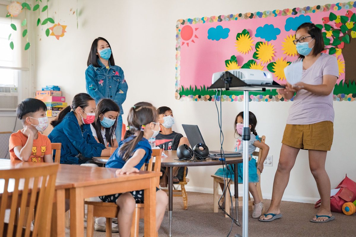 Children sitting around tables in the Sunday school classroom with their teachers