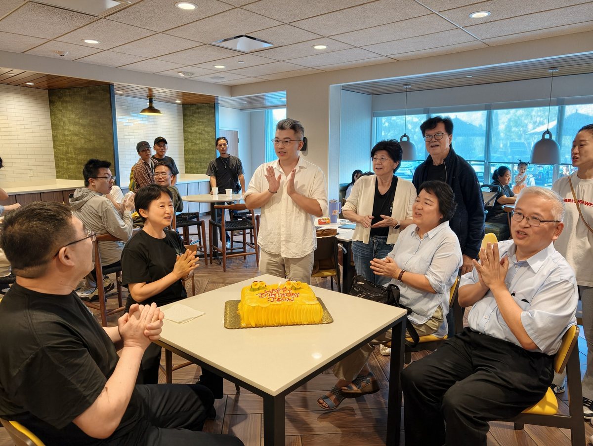 大家围着桌上的生日蛋糕鼓掌,长辈坐在一旁